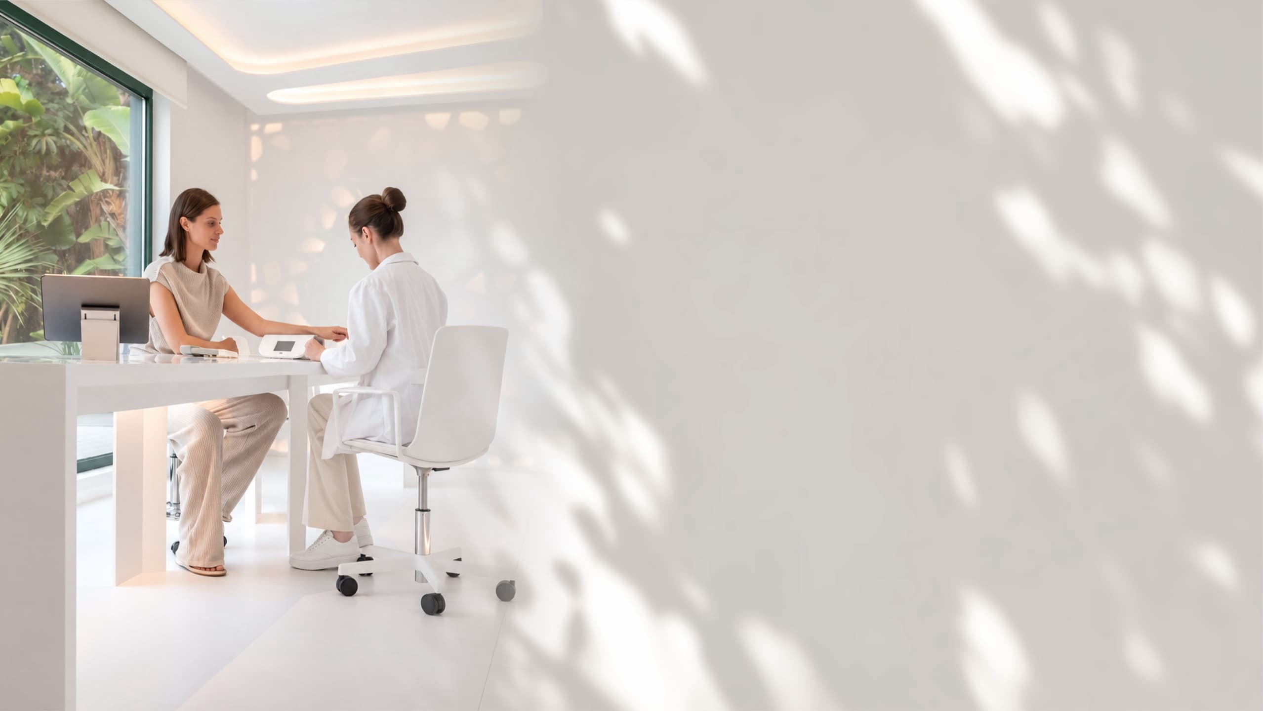 Two women talking across a white desk in a bright, quiet room